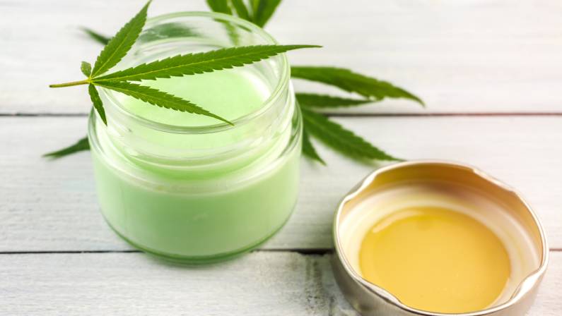 CBD Cannabis Hemp topical cream balm with cannabis leafs on wooden table