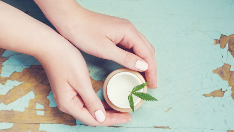 Cannabis cream with marijuana leaf in hands. Concept of herbal alternative medicine, cbd oil, pharmaceptical industry, cannabis cosmetics
