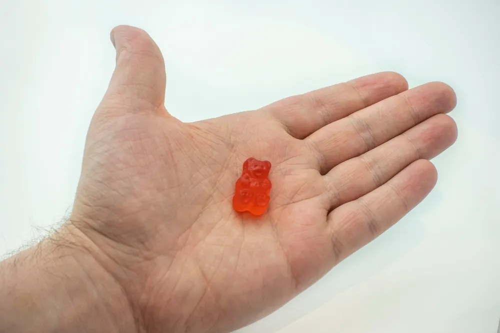 A colorful CBD infused medicinal candy gummy used for healing in the palm of a male