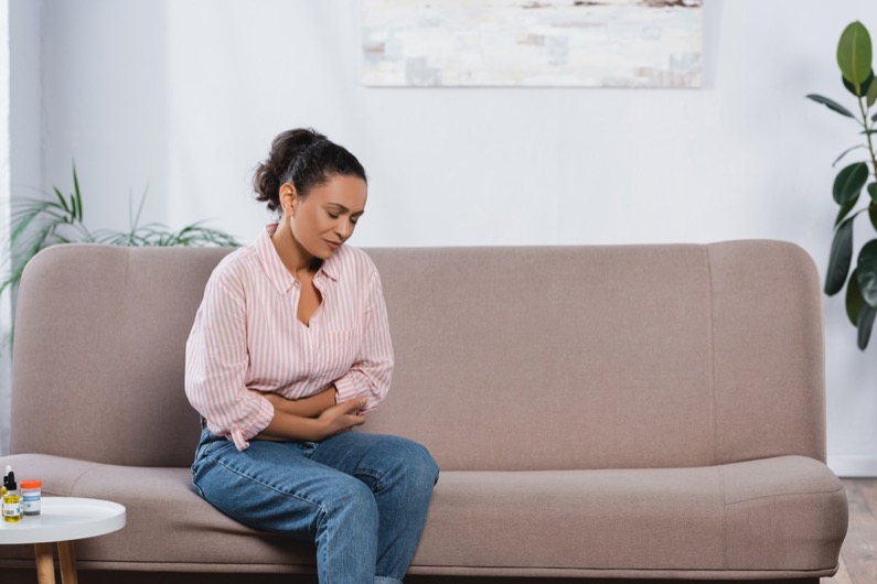 african american woman suffering from abdominal pain in living room