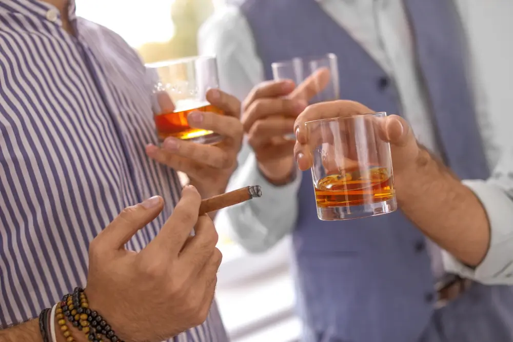 Group of friends drinking whiskey together indoors, closeup